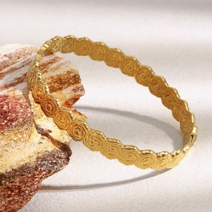 Dettaglio del bracciale in acciaio dorato 18K con rilievo floreale su pietre naturali
