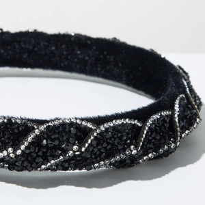 Dettaglio macro del cerchietto in velluto intrecciato con densi strass neri e chiari