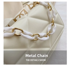 Close-up of white quilted handbag featuring acrylic and gold metal chunky chain