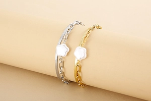 Detail of double-layer snake chain bracelet with white flower pearl charm on beige display