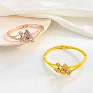 Detail von Schmetterlingsarmreifen in Gold und Roségold mit funkelnden bunten Kristallen