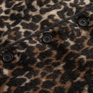 Detail of leopard print woolen vest showing button closure and black fabric piping finish
