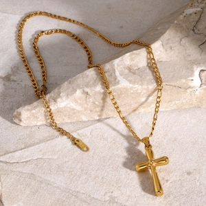 Gros plan d'un pendentif croix en acier inoxydable plaqué or 18 carats avec chaîne Figaro