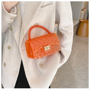 Detail of orange jelly bag featuring quilted texture, pearl handle, and gold chain strap