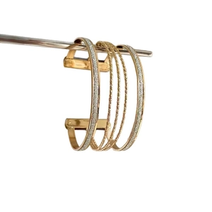 Minimalist multi-layer gold open bangle with sparkling metallic finish on white background