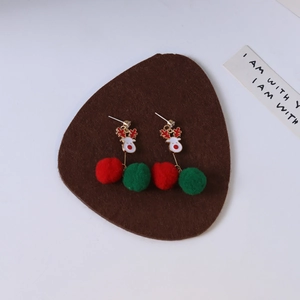 Close-up of asymmetric Christmas reindeer earrings with festive red and green plush balls