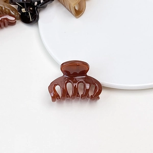 Close-up of a brown jelly texture mini hair claw clip on a white ceramic plate