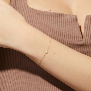 Nahaufnahme eines minimalistischen goldenen Silberarmbandes mit Opalstein am Handgelenk