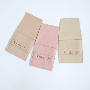 Three suede microfiber jewelry pouches in beige and pink with embossed logos on white background