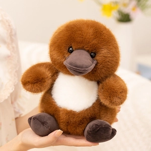 Close-up of soft brown platypus plush toy with gray beak being held in hand