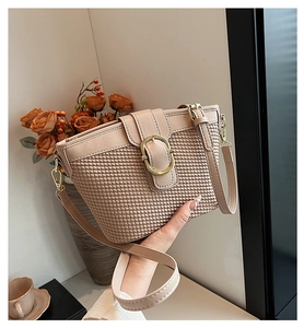Detail of beige quilted woven texture and gold round buckle on fashionable shoulder bag