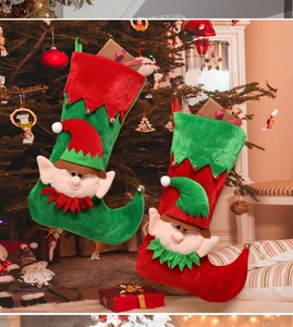 Detail of Christmas elf stockings hanging on a tree with festive bells and velvet texture