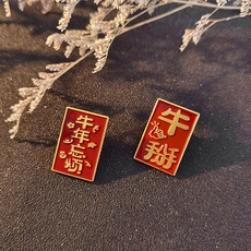 Detail of red enamel badges with gold Chinese text on a textured black surface