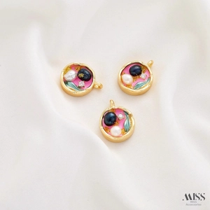 Macro detail of vintage floral enamel pendants with pearls on white silk fabric