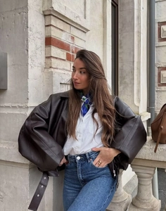 Street style shot of a dark brown oversized leather jacket with a blue patterned scarf