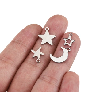Handheld view of four silver stainless steel star and moon charms for DIY jewelry making