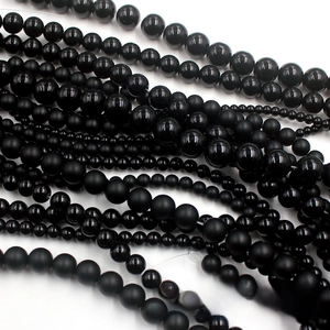 Detailed view of polished and matte black glass round beads for DIY jewelry making