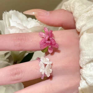 Detailed view of handmade beaded rings featuring pink and white resin flower designs