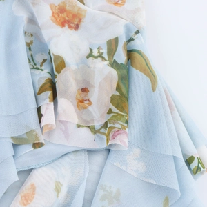 Détail du tissu en maille bleu clair avec imprimé fleuri et texture fluide