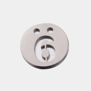 Vue macro d'un pendentif rond en acier poli avec chiffre 6 ajouré et deux trous de fixation
