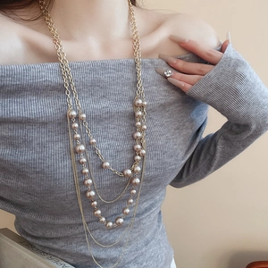 Detail of elegant multi-layered champagne faux pearl necklace on a grey sweater