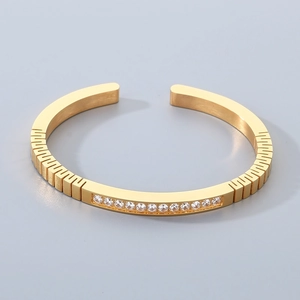 Gold stainless steel open bangle featuring cubic zirconia inlay and brushed metal texture