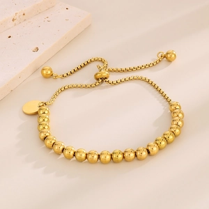 Gros plan d'un bracelet à billes d'or 18 carats avec fermoir coulissant et chaîne vénitienne