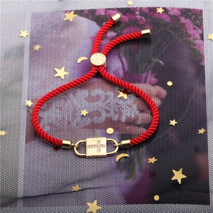 Adjustable red rope bracelet featuring a gold cross-inlaid lock charm with zircon accents