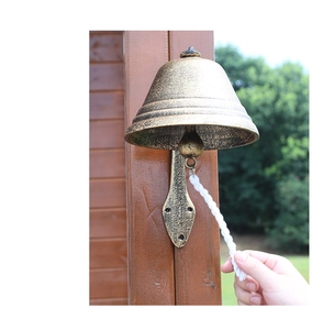 Close-up of vintage cast iron garden doorbell with aged texture and white cotton pull rope
