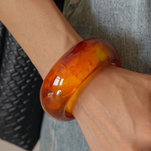 Detailed view of amber resin bangle with thick geometric design and cloudy texture