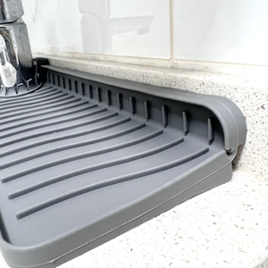 Gray silicone faucet draining mat with ridges placed on quartz bathroom countertop