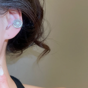 Detailed close-up of a silver zircon flower ear cuff worn on the cartilage without piercing