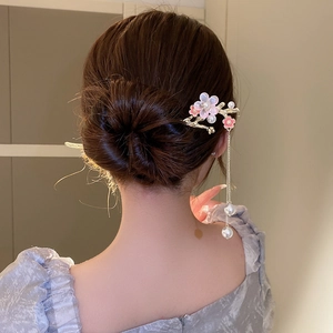Détail d'un pic à cheveux fleur rose avec de longs pompons et perles sur un modèle