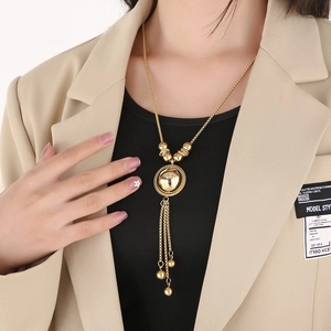 Detail of a vintage golden spherical tassel pendant necklace worn by a fashion model