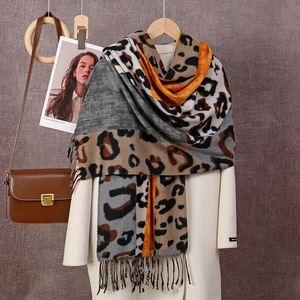 Détail d'une écharpe en cachemire à imprimé léopard gris et orange avec franges