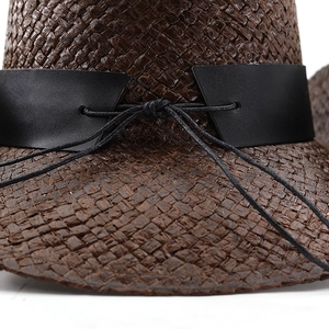 Détail d'un chapeau de cowboy en paille marron foncé avec ruban décoratif en similicuir