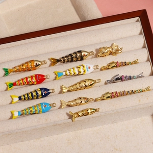 Pendentifs carpe koi dorés avec émail et zircons présentés dans un plateau à bijoux