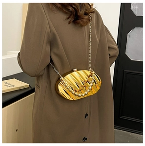 Detail of gold shell evening bag with pleated texture and round bead top handle strap