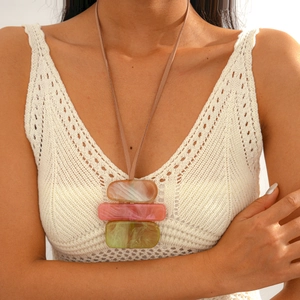 Close-up of geometric acrylic necklace with pink and green marble textures on model