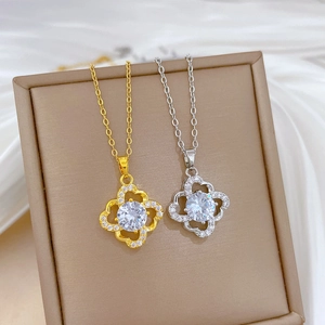 Elegant gold and silver four-leaf flower necklaces with crystals on silk background