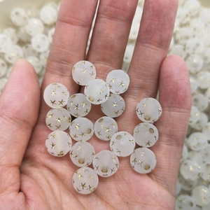 8mm frosted white acrylic star beads with gold patterns held in hand for DIY jewelry