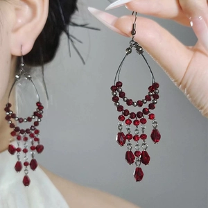 Elegant long tassel earrings with red water drop beads and gunmetal finish on a model