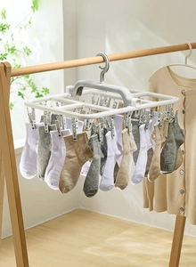 Close-up of foldable drying rack with clips holding socks on a balcony clothes rod