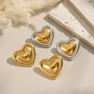 Elegant vintage heart stud earrings in gold and silver finish on stone tray