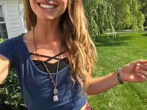 Outdoor shot showing a woman wearing a braided cord necklace with pink and blue raw crystals