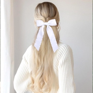 Elegant white satin oversized bow hair clip with long streamers on blonde wavy hair