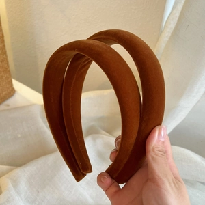 Close-up of two caramel brown velvet headbands with soft flocking texture on a white cloth