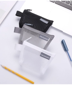 Three mesh coin purses in black, gray, and white on a desk showing mesh texture and zippers