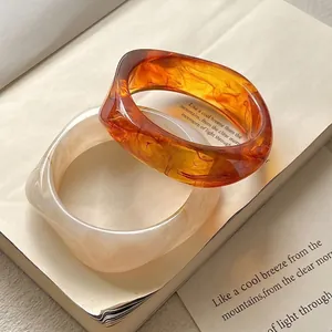 Detail of amber tortoiseshell and creamy marble resin bangles on vintage book