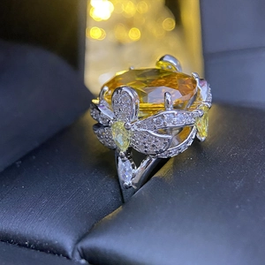Macro shot of large oval yellow gemstone in ornate floral silver setting on black velvet